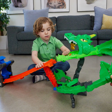 Child playing with the Hot Wheels Monster Trucks Dragon Destruction Playset on a living room floor