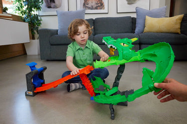 Child playing with the Hot Wheels Monster Trucks Dragon Destruction Playset on a living room floor
