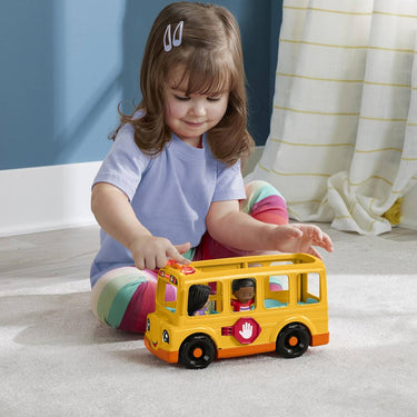 Toddler pushing a Little People school bus on the floor