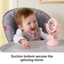 Baby in a high chair smiling at the pink spinning mirror with suction base