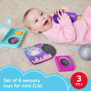 Baby lying on a rug holding the microphone toy with the other DJ set pieces nearby