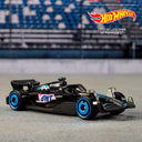 Black Formula 1 die-cast car with blue wheels and pink accents from the Hot Wheels 5-pack on a racetrack backdrop