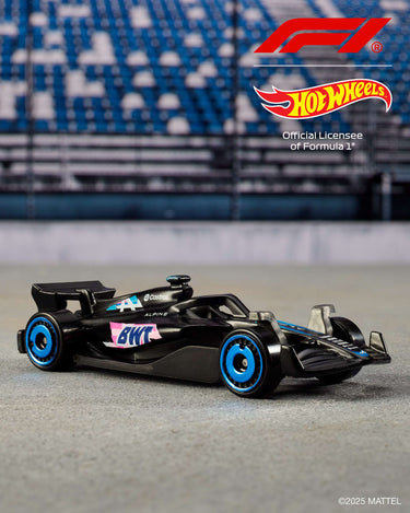 Black Formula 1 die-cast car with blue wheels and pink accents from the Hot Wheels 5-pack on a racetrack backdrop