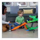 Two children playing with the Hot Wheels Dragon Destruction playset and monster trucks on a living room floor