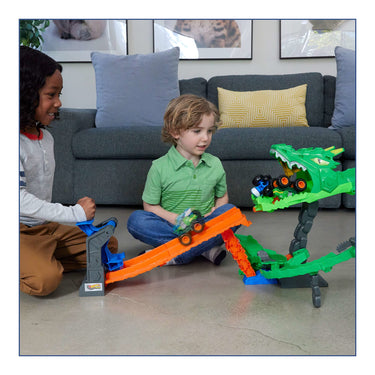 Two children playing with the Hot Wheels Dragon Destruction playset and monster trucks on a living room floor