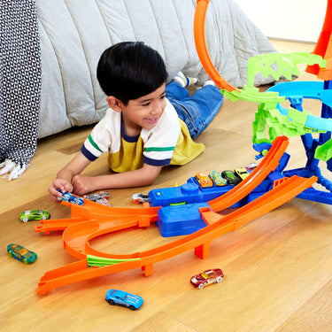 Child lying on the floor playing with the Mid-Air Crash track set and toy cars
