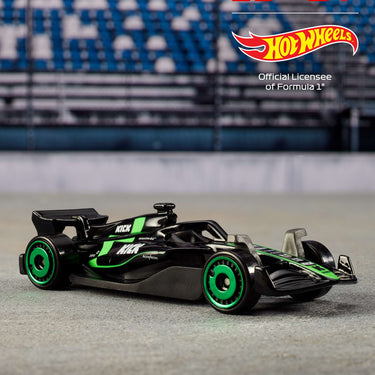 Black and green Formula 1 die-cast car from the Hot Wheels 5-pack on a racetrack backdrop