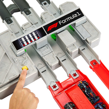 Finger pressing the button on the Formula 1 booster with F1 cars on the red track
