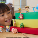 Child smiling at Toy Story Small Stars mini figures displayed on stacked books