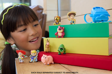 Child smiling at Toy Story Small Stars mini figures displayed on stacked books