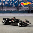 Black Formula 1 die-cast car with white wheels from the Hot Wheels 5-pack on a racetrack backdrop