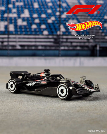 Black Formula 1 die-cast car with white wheels from the Hot Wheels 5-pack on a racetrack backdrop
