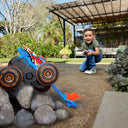 Child driving the Tiger Shark Climber RC truck as it climbs over rocks outdoors