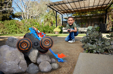 Child driving the Tiger Shark Climber RC truck as it climbs over rocks outdoors