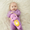 Baby lying on a blanket hugging the Soothe & Glow Seahorse