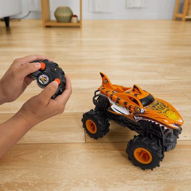 Child driving the RC Tiger Shark monster truck across a wood floor with the remote