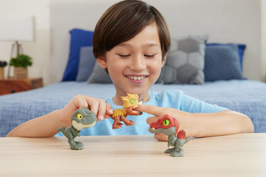 Child playing with three Mighty Little Biters dinosaur figures on a table