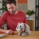 Man at a table with the Dennis wolf plush holding the bone in its mouth