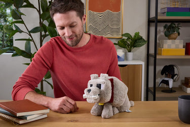 Man at a table with the Dennis wolf plush holding the bone in its mouth