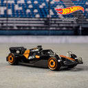 Black and orange Formula 1 die-cast car from the Hot Wheels 5-pack on a racetrack backdrop
