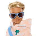 Close-up of Ken doll with rooted blonde hair wearing blue sunglasses and a palm tree hoodie