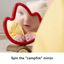 Baby looking into the red campfire-shaped mirror toy