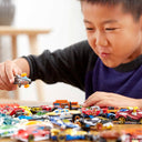 Boy playing with a table full of Hot Wheels die-cast cars
