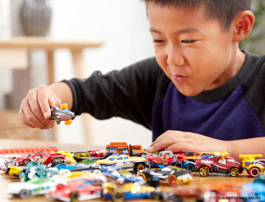 Boy playing with a table full of Hot Wheels die-cast cars