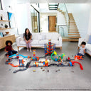 Family playing with a large layout of connected Hot Wheels track sets in a living room