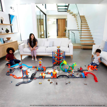 Family playing with a large layout of connected Hot Wheels track sets in a living room