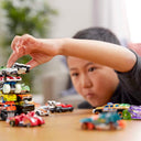 Child stacking Hot Wheels cars into a tall tower on a table