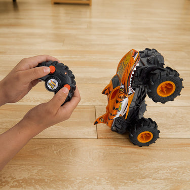 RC Tiger Shark monster truck popping a wheelie on the floor while a child steers